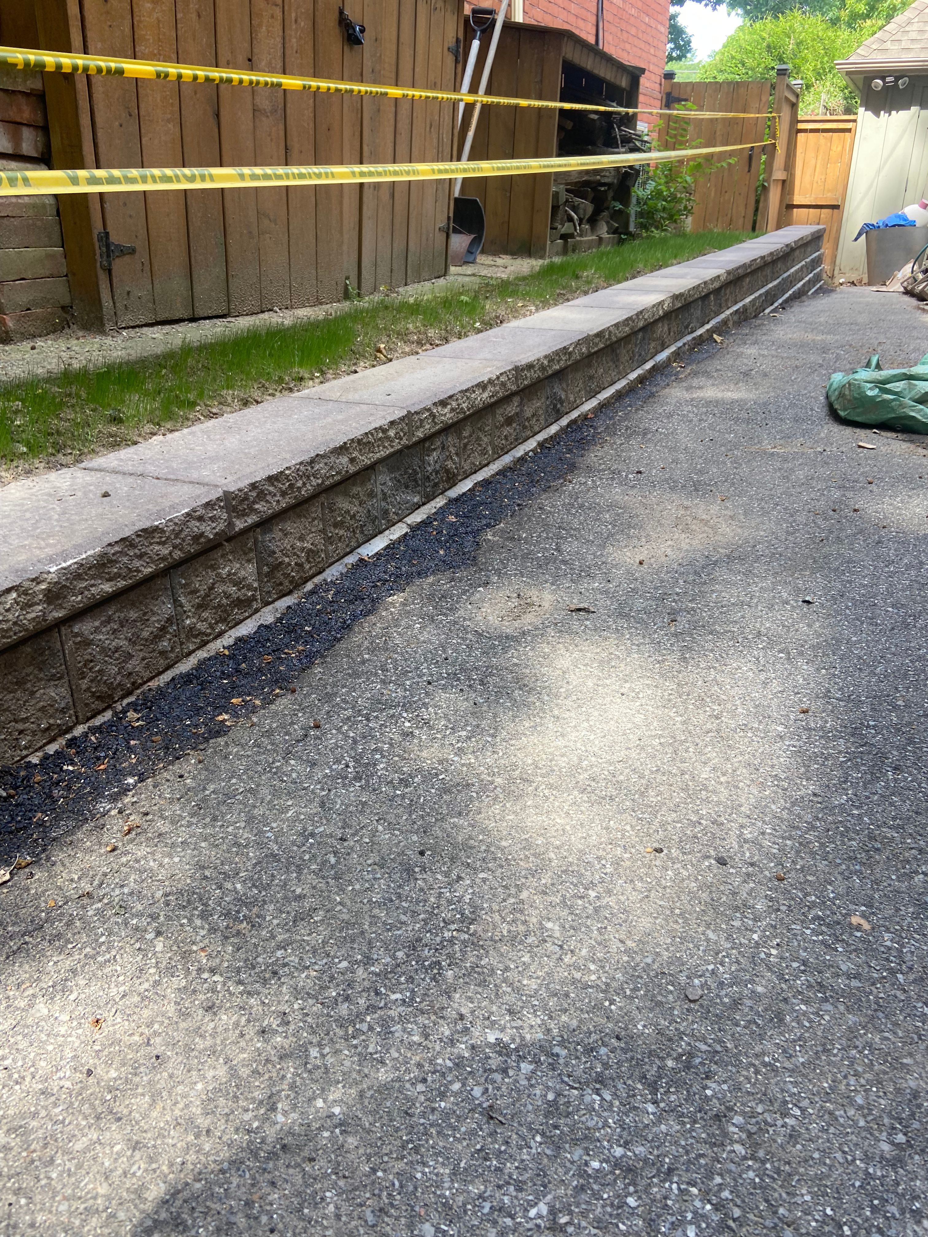 Full view of a functional block retaining wall along a driveway.